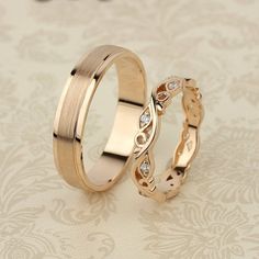 two gold wedding rings with diamond accents on a floral background, set against each other