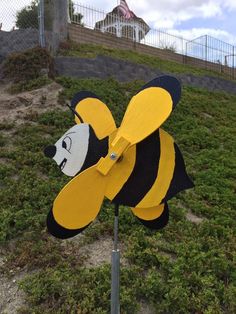 a yellow and black bee on top of a green field next to a metal pole