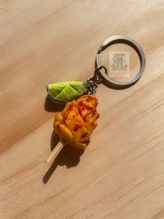 a keychain with a piece of food on it sitting on top of a wooden table