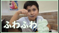 a young boy holding a spoon in front of his face while sitting at a table