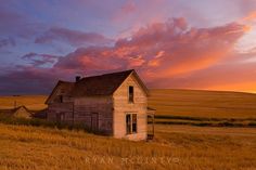 an old run down house sits in the middle of a wheat field at sunset or dawn