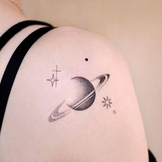 a woman's shoulder with a saturn tattoo on it and stars around the planet