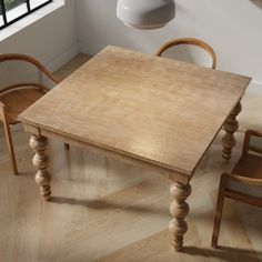 a wooden table and chairs in front of a window