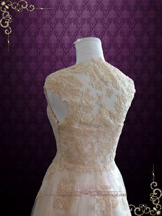 the back of a white wedding dress on a mannequinl stand in front of a purple wall