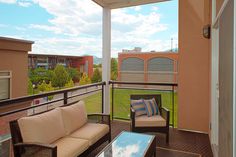 a balcony with chairs, tables and couches on it's side overlooking a grassy area