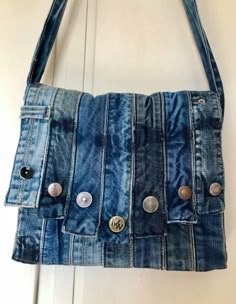 a purse made out of old jeans hanging on a door handle with buttons in the pocket