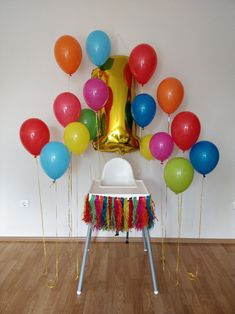 there are many balloons and streamers on the floor in front of a white chair