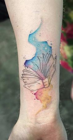 a watercolor tattoo on the foot of a woman with an open book in it