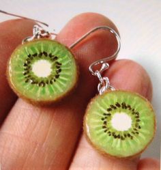 a pair of green earrings with a kiwi cut in half