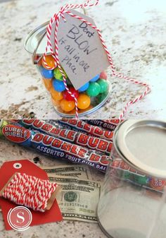 candy in a glass jar with a note attached to it and some candy on the counter