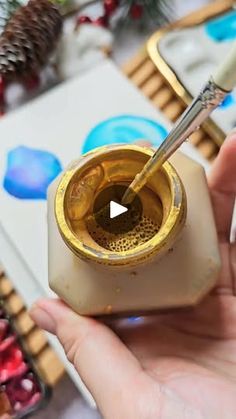 someone is holding a paintbrush in their hand and painting the inside of a jar