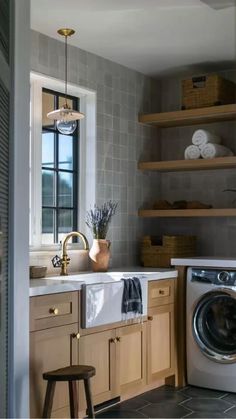 a washer and dryer in a small room with shelves on the wall behind them