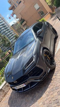 a grey sports car parked on the side of a road next to a tall building