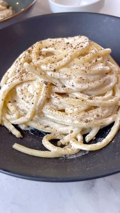 some kind of food that is in a black plate on a table with silverware