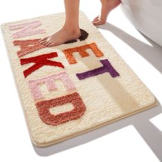 a person standing on a bath mat that has letters and numbers written in different colors