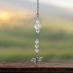 a glass beaded necklace with dragon charms hanging from it's side on a wooden surface