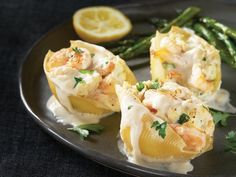 some food is sitting on a plate with asparagus and lemon wedges next to it