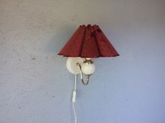 a red lamp hanging from the side of a wall with a cord attached to it