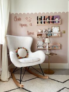 a white rocking chair in front of a pink wall