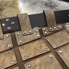 several pieces of leather with metal rivets on them sitting on a fur rug