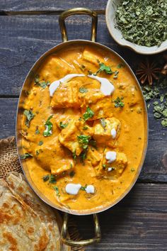 a pan filled with chicken curry next to some pita bread