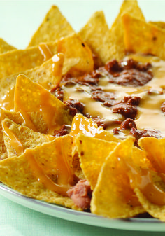 a plate filled with nachos covered in cheese and toppings on top of tortilla chips