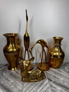 gold colored vases and sculptures are sitting on the floor