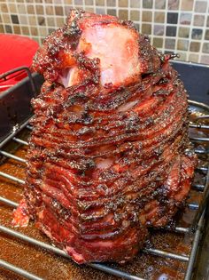 a large pile of meat sitting on top of a metal rack next to a frying pan