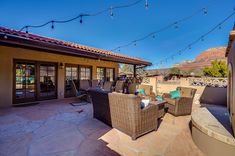 an outdoor patio with wicker furniture and string lights