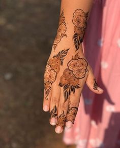 a woman's hand with henna tattoos and flowers on her left arm,