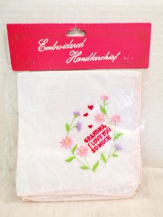 the package is packaged in plastic and has pink flowers on white fabric with green leaves