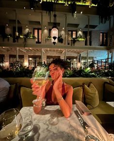 a woman sitting at a table with a glass of wine in front of her face