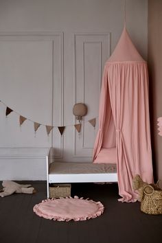 a pink canopy bed sitting next to a white bench and rug on top of a hard wood floor