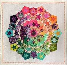 a multicolored patchwork quilt is displayed on a wall