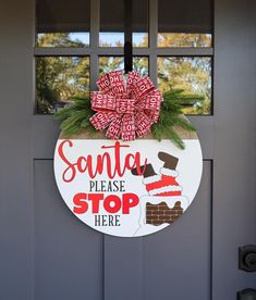 a santa please stop here sign hangs on the front door to give someone some christmas cheer