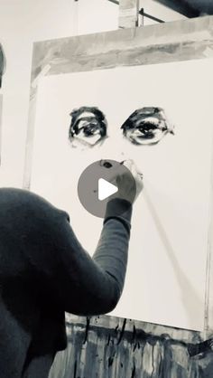 a man is painting an image on a canvas with his eyes drawn in black and white