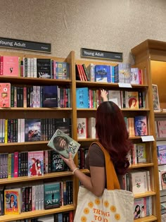 a woman is looking at books in a book store while holding a tote bag