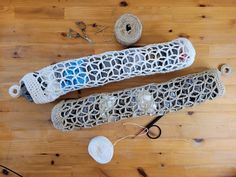 two crocheted objects sitting on top of a wooden floor next to yarn and scissors