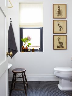 a white toilet sitting in a bathroom next to a window with pictures on the wall