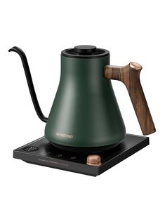 a green tea kettle sitting on top of a black stove with a wooden spoon sticking out of it