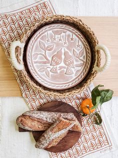 two loaves of bread sitting on top of a wooden cutting board next to an orange flower