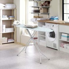 an ironing board sitting on top of a wooden table next to a dryer