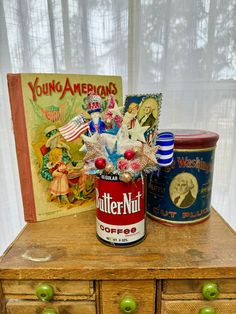 an old wooden table with two tins on it and a book in the background