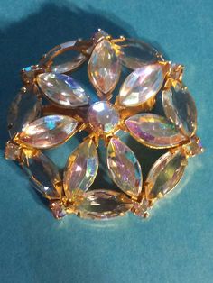 If you love jewelry, you will love this stunning iridescent aurora borealis crystal brooch.  This vintage aurora borealis crystal pin is probably from the 50's or 60's.  It is shaped like a flower in a round border of AB crystals in mostly marquis shapes on a goldtone finish.  The pin measures about 2 inches across.  These type of vintage pins are hard to photograph and the photos don't do them justice, especially the opalescent finishes. This pin is very cute and would look great on a blazer, jacket, hat or coat.   These are great for the vintage jewelry collector, or as a gift for someone who loves glitzy jewelry and is not afraid to be seen. Please note, all vintage pieces will have some irregularities, and possible discolorations, so please check the photos carefully before you purchas Rhinestone Stuff, Round Border, Vintage Jewellery Rings, Aurora Borealis Crystal, Love Jewelry, Crystal Brooch, Vintage Pins, Vintage Costume Jewelry, Aurora Borealis