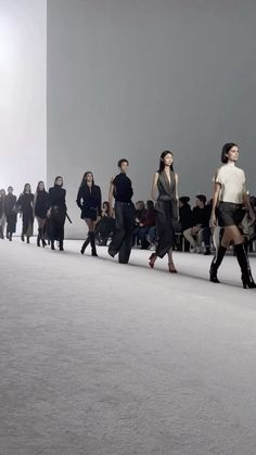 several models walking down the runway in black and white outfits, all wearing high heeled boots