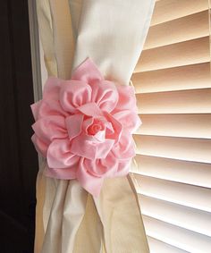 a pink flower sitting on top of a window sill next to a blindshade