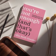 a pink book sitting on top of a table next to a knife and some flowers