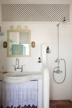 a bathroom with a sink, mirror and shower head mounted on the wall above it