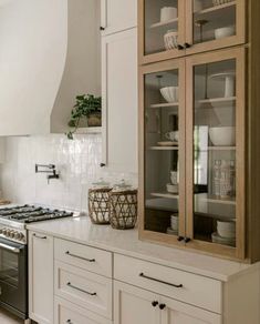 a kitchen with white cupboards and an oven in the center, filled with dishes