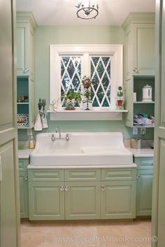 a white sink sitting under a window in a kitchen next to green cabinets and cupboards